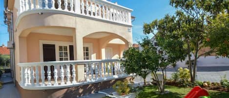 A two-story building with a balcony, a slide, and a garden.