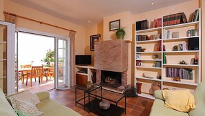 A living room with a fireplace, a television, and a bookshelf filled with books. - Vacation home Zen by Interhome (Tossa de Mar)