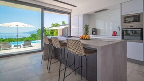 Eine moderne Küche mit einer großen Kochinsel, Barhocker und Meerblick.