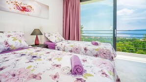 Ein modernes Schlafzimmer mit zwei Betten, einem großen Fenster mit Blick auf die Stadt und einem dekorativen Wandbild.