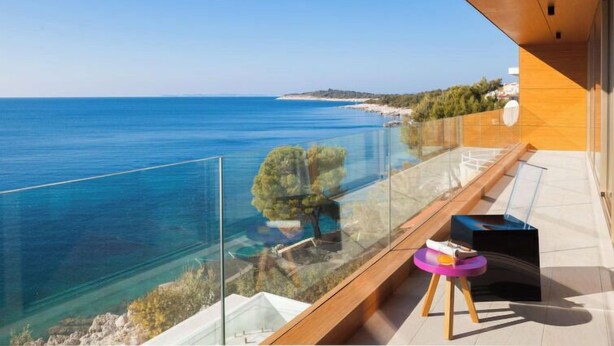 A balcony with a clear view of the sea and a distant coastline.