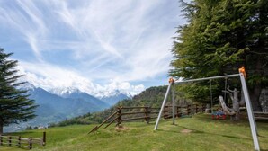 A grassy outdoor area with a swing set and a wooden fence. - Hérisson by Interhome (Sarre)