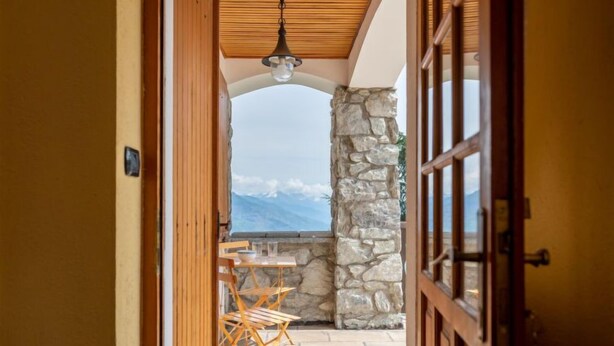 A corridor leading to a patio with a stone wall and a table with chairs. - Hérisson by Interhome (Sarre)