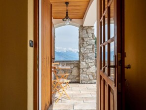 A corridor leading to a patio with a stone wall and a table with chairs. - Hérisson by Interhome (Sarre)
