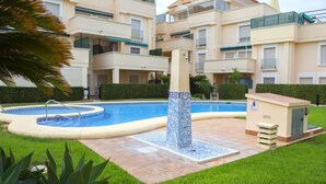 Un edificio residencial con piscina, una fuente de azulejos y un pequeño cobertizo de servicio.