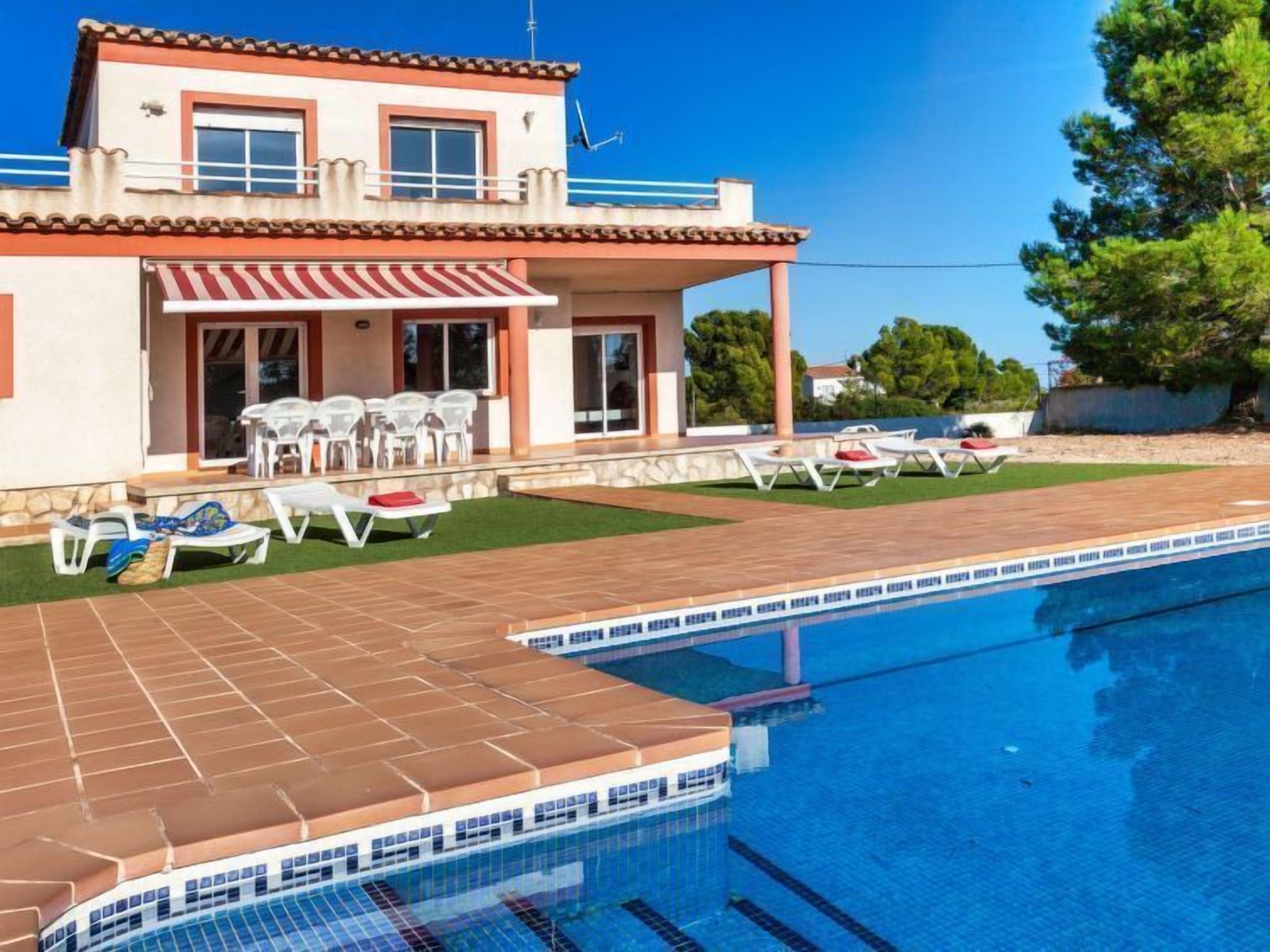 A two-story building with a swimming pool, outdoor seating, and a covered patio area.