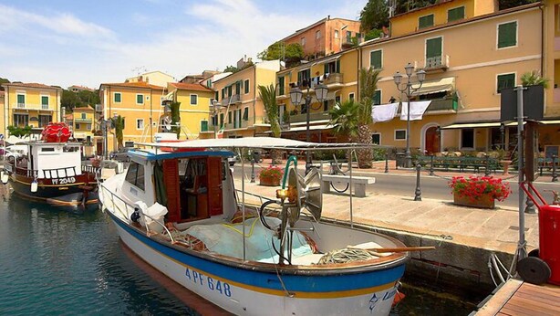 A boat docked at a marina with a wooden deck and a small cabin.