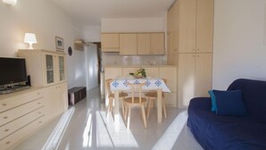 A compact living space with a dining area, kitchenette, and a sofa.