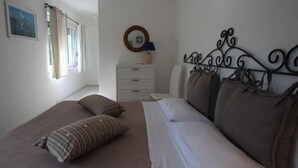 A bedroom with a bed, two pillows, a dresser, a mirror, and a window with curtains. - Rosemarie by Interhome (Lago di Ledro)