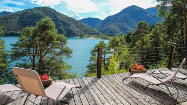 A wooden deck with two lounge chairs overlooking a lake and mountains. - Rosemarie by Interhome (Lago di Ledro)