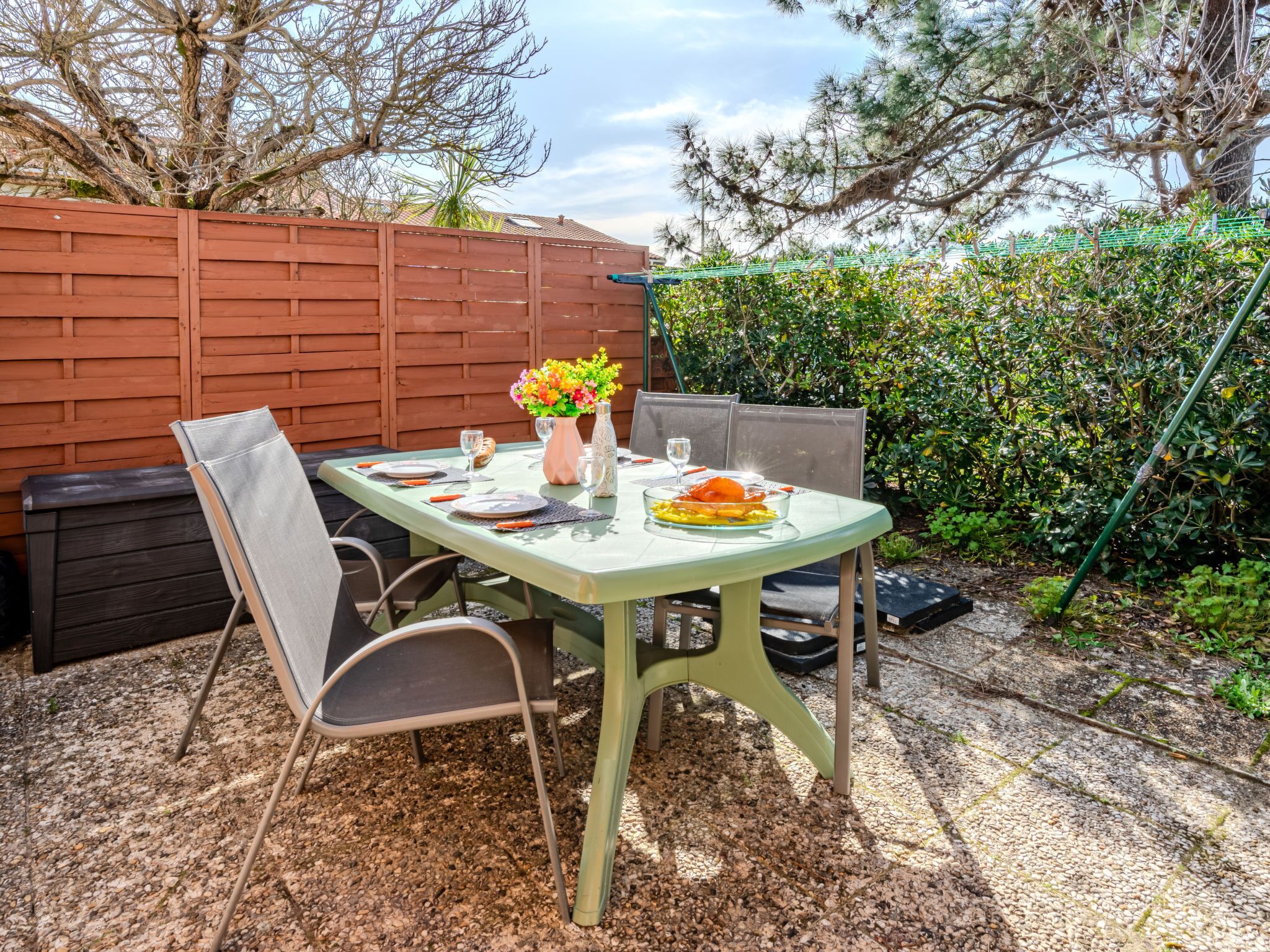 A table set outdoors with a vase of flowers, plates, and cutlery.