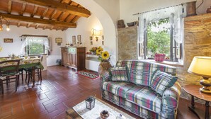 Um quarto aconchegante com teto de madeira, sofá xadrez, mesa de jantar com cadeiras e parede de pedra.