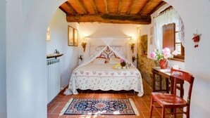 Quarto com uma cama, uma cadeira, uma mesa e uma janela.