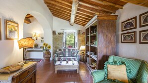 Uma sala de estar aconchegante com teto de madeira, sofá xadrez, poltrona verde e mesa de centro.