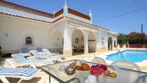A poolside area with lounge chairs, a table with a drink and pastries, and a pool. - Vacation home Alan by Interhome (Albir)