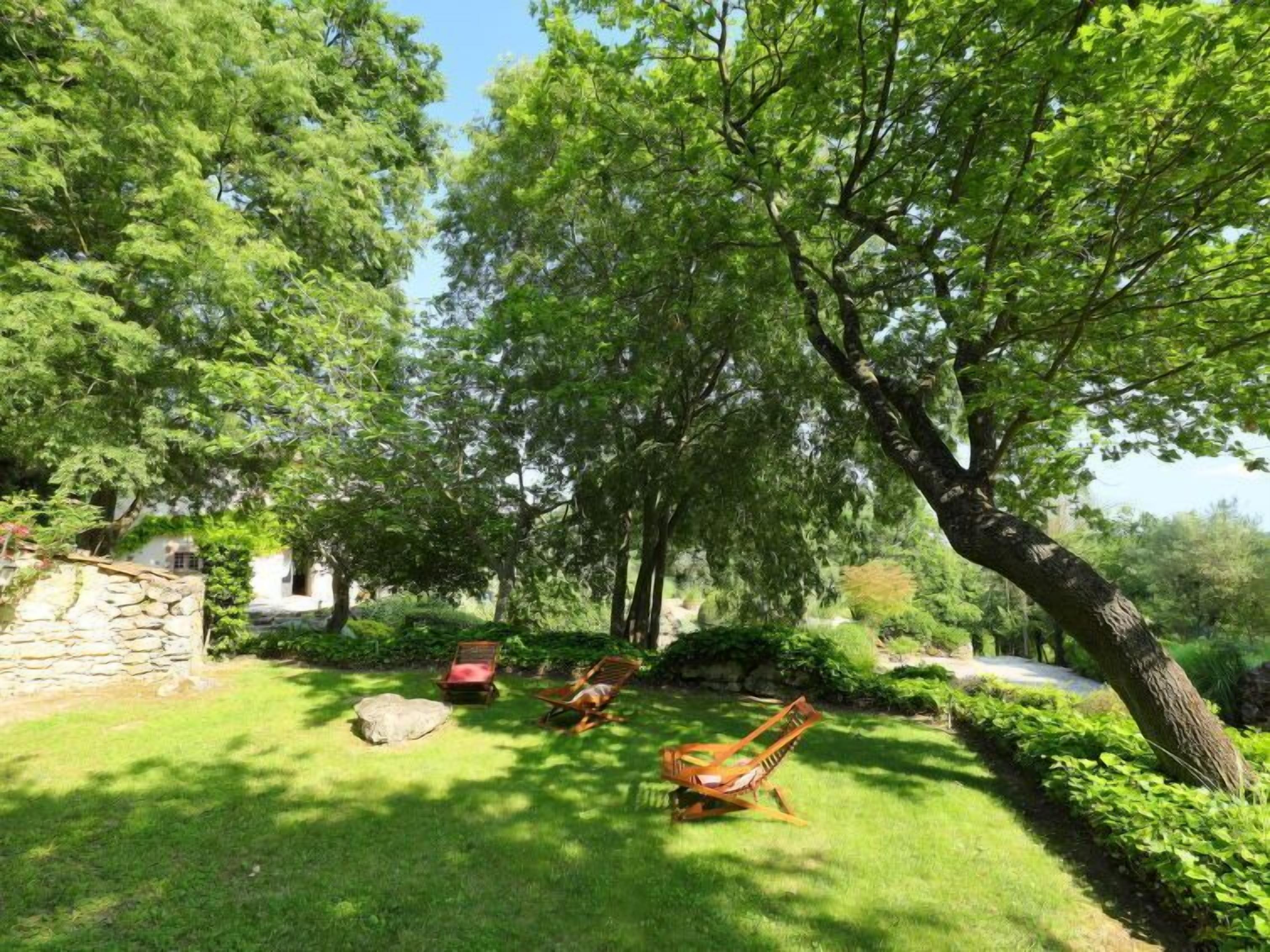 A lush garden with a stone wall, a wooden swing, and a pathway.