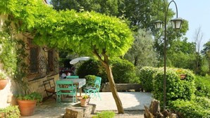 A patio area with a table and chairs, surrounded by potted plants and a pergola. - Vacation home Oasis by Interhome (Penna in Teverina)