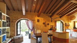 A rustic interior with a stone wall, wooden beams, a dining area with a table and chairs, and a kitchen counter. - Vacation home Oasis by Interhome (Penna in Teverina)