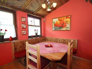 A cozy room with a wooden bench seating area, a table with a pink tablecloth, and a large painting of flowers on the wall.