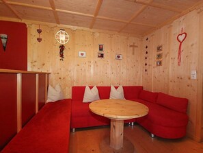 A cozy room with a red sofa, a wooden table, and various wall decorations including hearts and a cross.