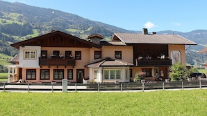Un chalet à deux étages doté d’un balcon, situé dans un cadre montagneux.