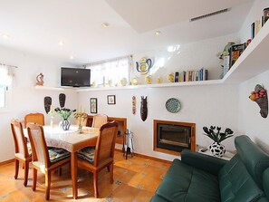A dining area with a table and chairs, a television above the table, and a fireplace.
