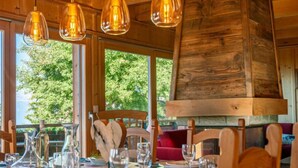A dining area with wooden furniture, clear glass pendant lights, and a view of greenery outside. - Rêves des Alpes by Interhome (Nendaz)
