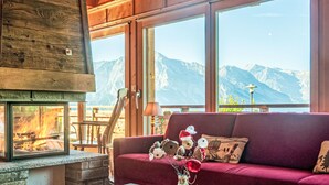 A cozy room with a fireplace, a red sofa, and a view of mountains. - Rêves des Alpes by Interhome (Nendaz)