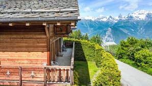 A wooden chalet with a balcony overlooking a mountain path and snow-capped peaks. - Rêves des Alpes by Interhome (Nendaz)