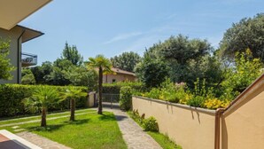 A courtyard with a stone pathway, green lawn, and various plants. - Antonia by Interhome (Marina Pietrasanta)
