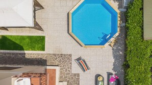 An octagonal pool with a blue interior, surrounded by a stone patio. There are two lounge chairs and a small table with items on it. - Antonia by Interhome (Marina Pietrasanta)