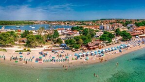 Une ville côtière dotée d’une plage, d’eaux cristallines et de bateaux amarrés dans le port.