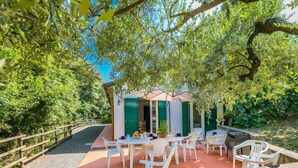 Una veranda esterna con mobili in plastica bianca, un tavolino e una porta verde.