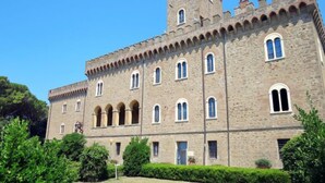 Un edificio storico in pietra con una torre centrale, diverse finestre ad arco e una facciata simmetrica.