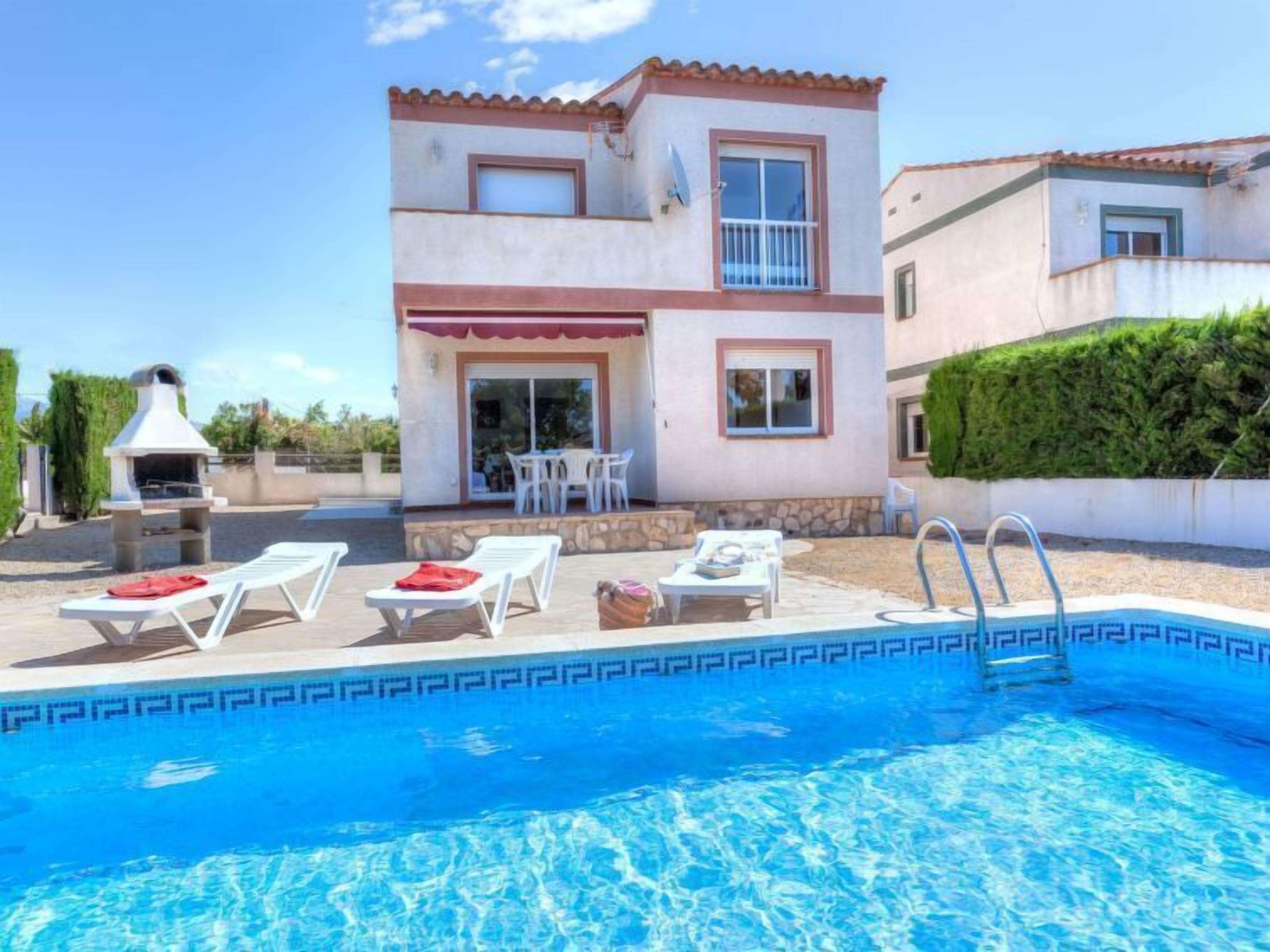 Una casa de dos pisos con piscina, mobiliario de exterior y zona de barbacoa.