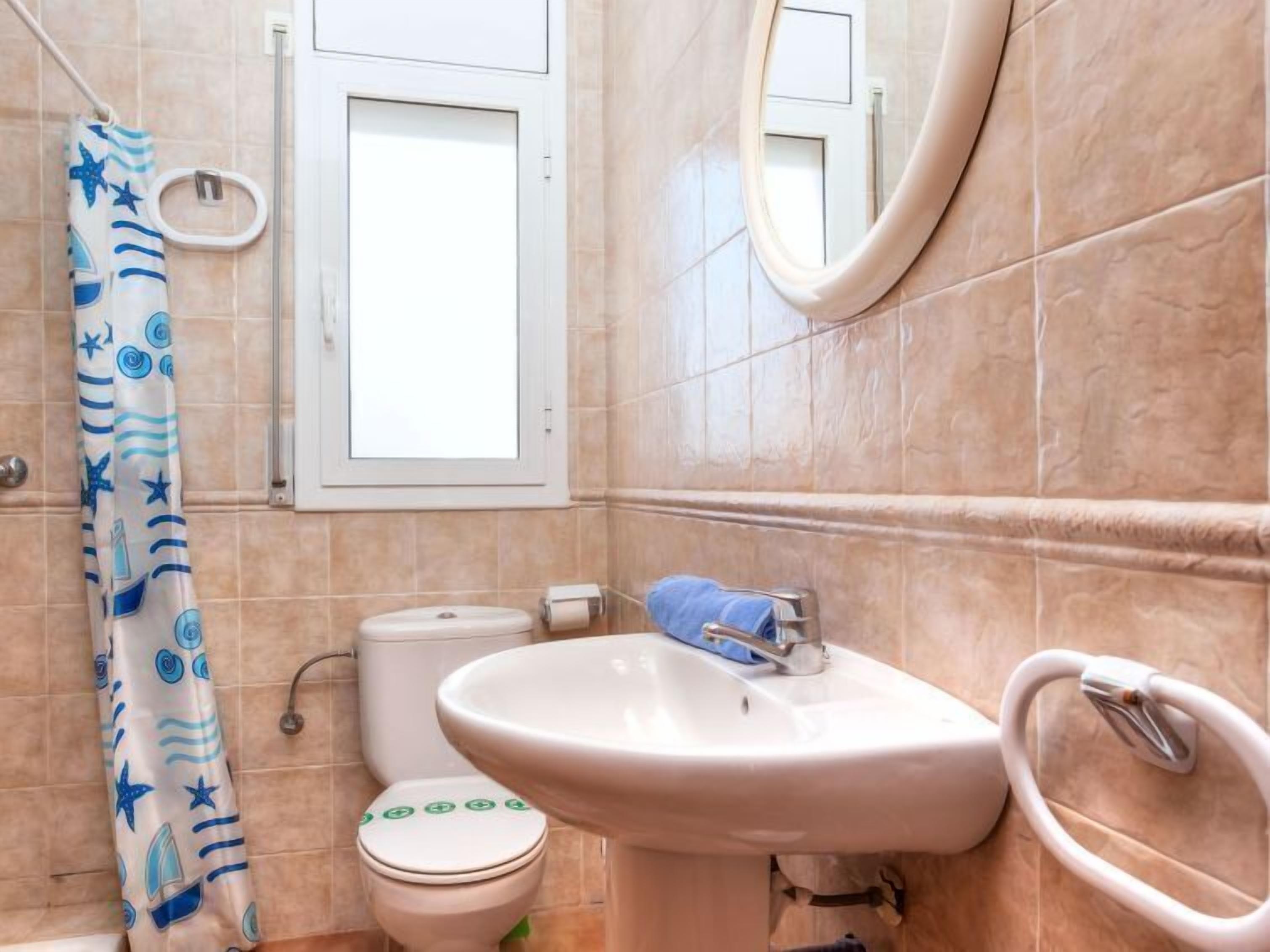 Een badkamer met toilet, wastafel en douchegordijn.