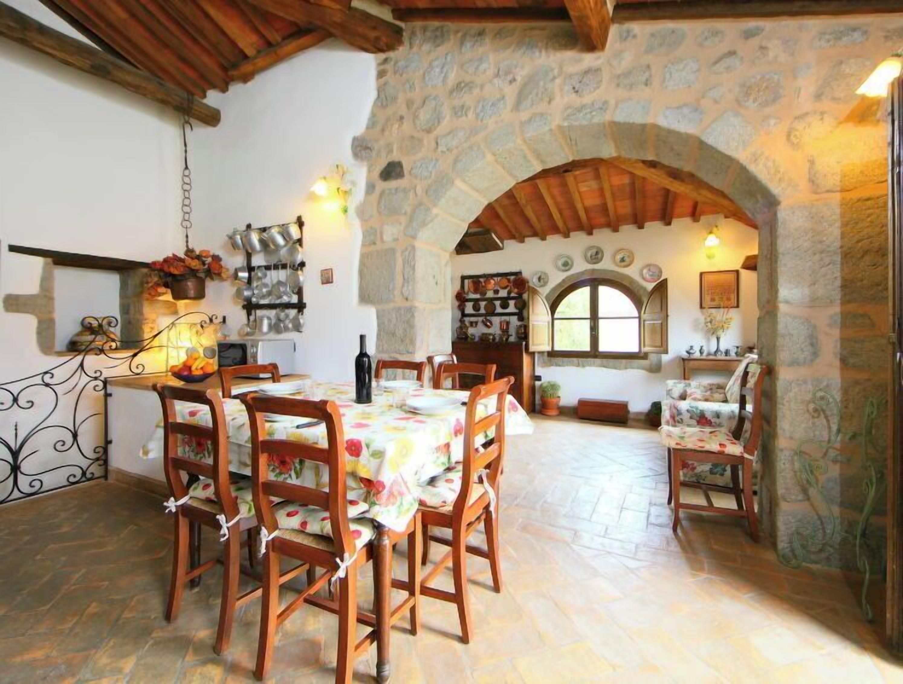 Un coin repas rustique avec des murs en pierre, des meubles en bois et une arche en pierre.