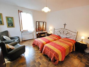 Une chambre avec deux lits, une chaise, un bureau et un miroir.