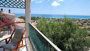 Ein Balkon mit Blick auf das Meer und eine darunterliegende Stadt.