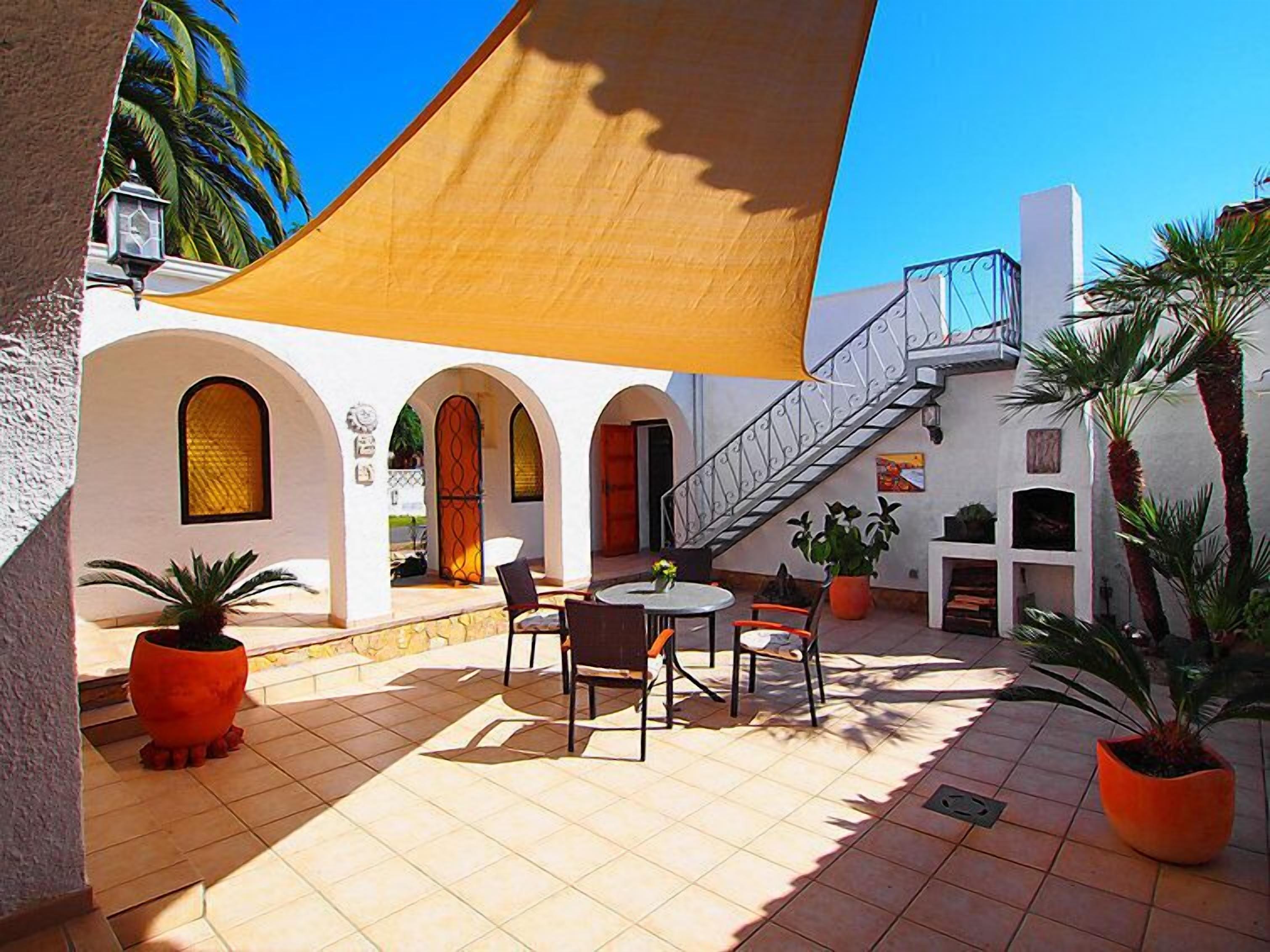 Un patio con una mesa, sillas, una escalera y plantas en macetas.