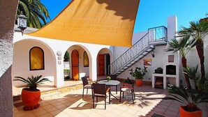 A courtyard with a table and chairs, a staircase, and potted plants. - Alberes by Interhome (Empuriabrava)