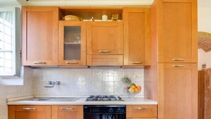 Een keuken met houten kastjes, een roestvrijstalen spoelbak, een gasfornuis en een vaatwasser.