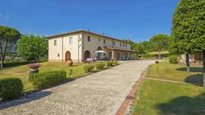 Een gebouw met twee verdiepingen en een verharde oprit die leidt naar een overdekt terras.