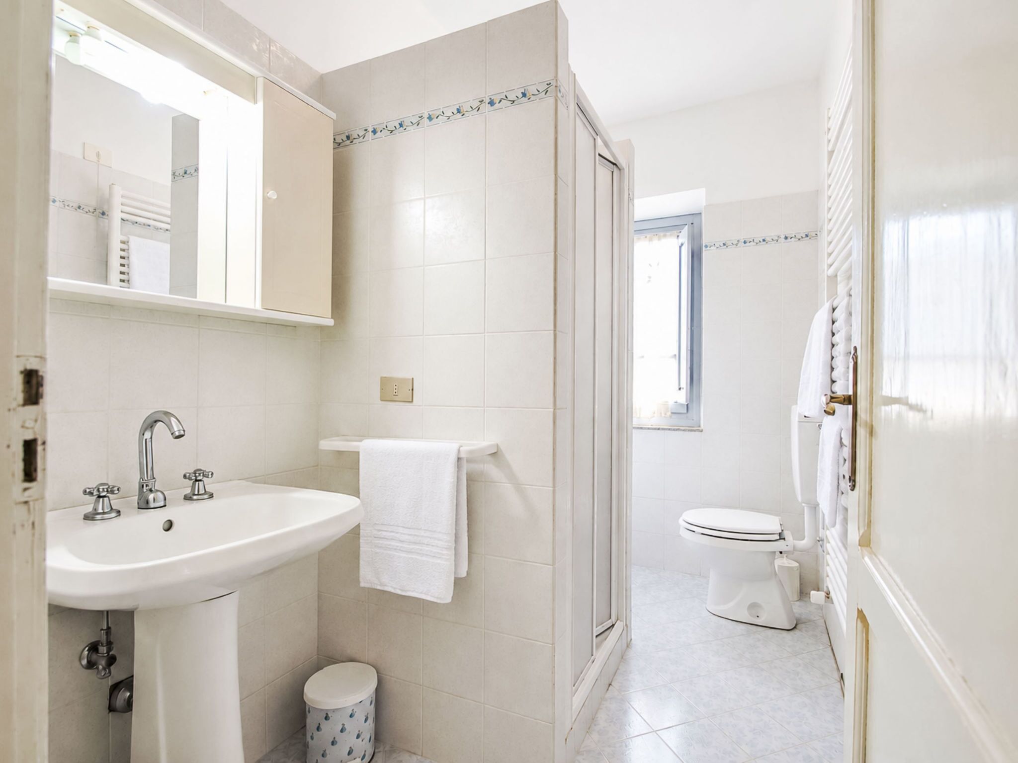 A bathroom with a sink, mirror, toilet, and shower area.