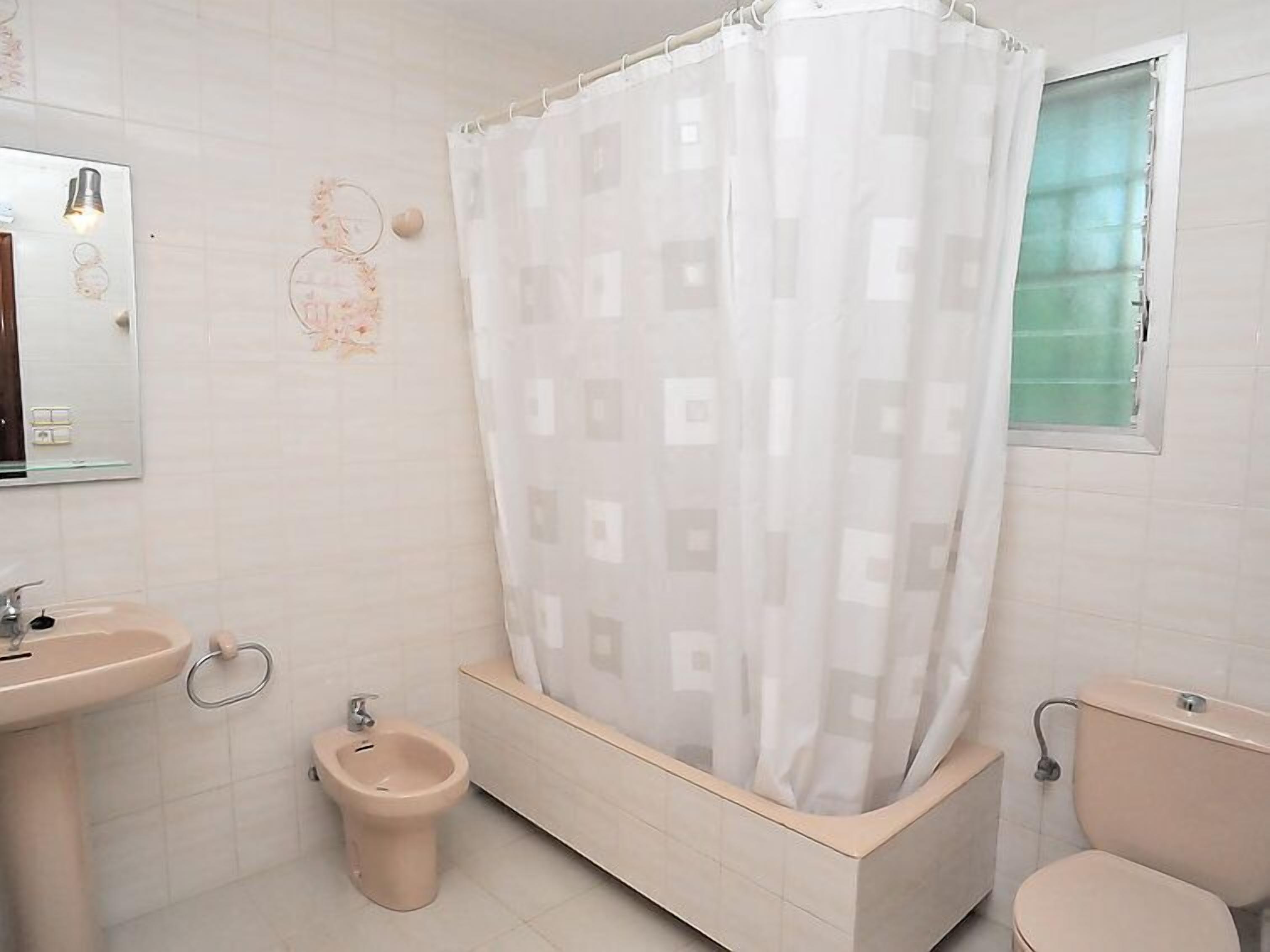 A bathroom with a bathtub, a bidet, a toilet, and a sink.
