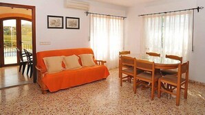Habitación con sofá, mesa de comedor, sillas y vistas a través de un ventanal.