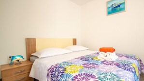 Un dormitorio con cama, mesita de noche, lámpara y un cuadro en la pared.