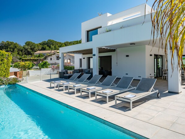 A modern poolside area with lounge chairs and a pool. - Xicoria by Interhome (Jávea)