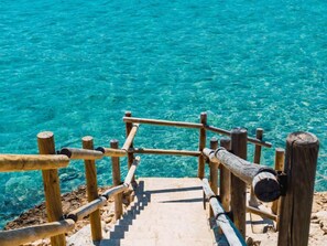 A wooden staircase leading into clear turquoise water.
