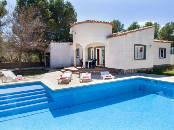 A modern villa with a swimming pool, outdoor seating, and a patio area.